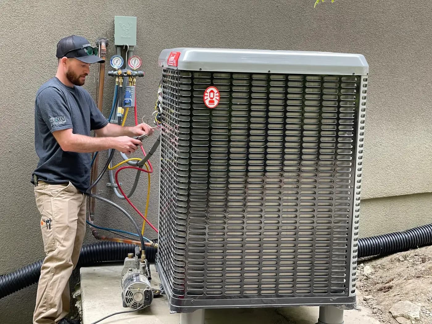 Photograph of a technician connecting gauges to a residential heat pump outdoor unit